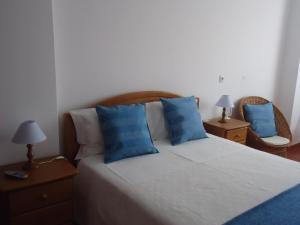 a bedroom with a large bed with blue pillows at Casa Mar Azul in Vila Nova de Milfontes