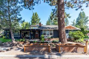 a house with two benches in front of a tree at The Bend House in Bend