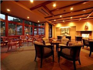a living room with tables and chairs and a fireplace at Hakuba Hotel Ougiya in Hakuba