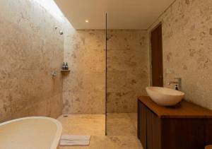 a bathroom with a tub and a sink and a shower at Natajiwa Village in Seminyak