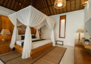 a bedroom with a bed with mosquito nets at Natajiwa Village in Seminyak