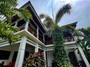 a building with a palm tree in front of it at Rock Pool Homestay in Huu