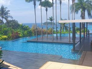 a swimming pool with palm trees and the ocean at The heights Penthouse Ocean view A11 Near Kata Beach in Kata Beach