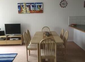 a dining room with a table and chairs and a television at 36 Maurice Avenue in Mallacoota