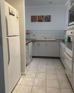a kitchen with white appliances and a tiled floor at 36 Maurice Avenue in Mallacoota