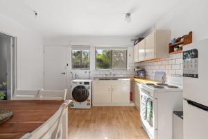 a kitchen with white appliances and a wooden floor at Little Pier Cottage in Inverloch