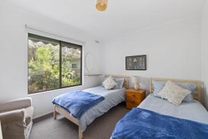 two beds in a room with a window at Little Pier Cottage in Inverloch