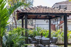 un patio con tavolo e sedie sotto un pergolato di Trezora Candolim - Luxury 4bhk villa with pool a Goa