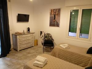 a bedroom with two beds and a dresser and a television at John's House in Sanremo