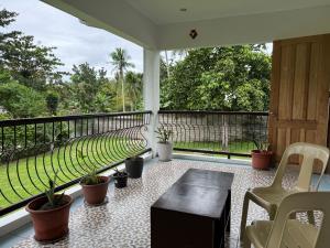 a porch with a table and chairs and a balcony with plants at CasaLinda Homestay in Agoho