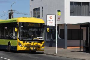 a yellow bus is parked at a bus stop at Airport Stays in Wellington