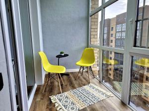 two yellow chairs and a table on a balcony at жк Атлант in Kokshetau