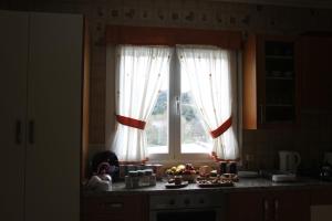 a kitchen with a window with white curtains and a counter at Venecia Bed&Breakfast in Villafranca del Bierzo