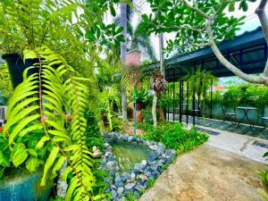 a garden with a pond and trees and plants at Rosie Garden & Home in Na Jomtien