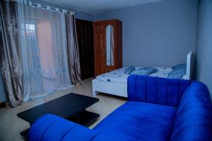 a blue living room with a couch and a bed at Cozy Studio Apartment Makindye in Kampala