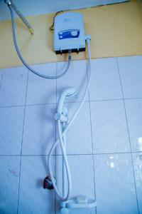 a shower in a bathroom with a hose on the wall at Cozy Studio Apartment Makindye in Kampala