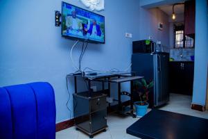 a living room with a desk and a tv on a wall at Cozy Studio Apartment Makindye in Kampala