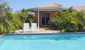 a house with two chairs and a swimming pool at La Boheme Aruba in Palm-Eagle Beach