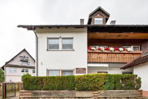een wit huis met bloemen op een balkon bij Haus Sommerberg in Titisee-Neustadt