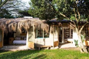 a small white house with a thatched roof at Hillside Retreat – Africa Amini Life in Usa River