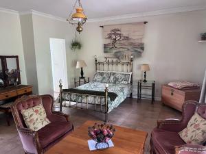 een slaapkamer met een bed, twee stoelen en een tafel bij Rondebosch Gardens in Humansdorp