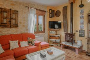 a living room with an orange couch and a tv at La Cardeñuela in Burgos