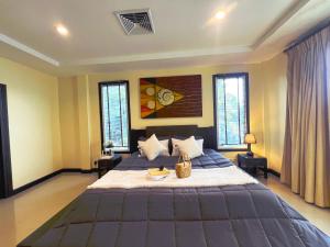 Un dormitorio con una cama grande en una habitación con ventanas. en Baan Chai Hadd, en Pattaya South 24 fotos más