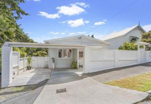 una casa blanca con una valla blanca en Auckland Bungalow Apartment, en Auckland