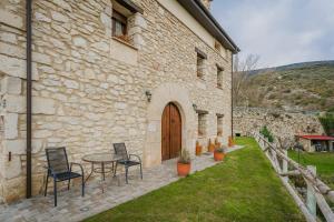 un edificio in pietra con tavolo e sedie in cortile di Torres 1 a Quintana de Valdivielso
