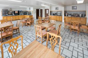 a restaurant with wooden tables and chairs and a kitchen at Red Lion Inn & Suites Auburn in Auburn