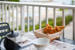 a basket of croissants and cups on a table at Studio Etoile De Mer - Vue mer in Villeneuve-Loubet