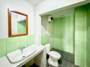 une salle de bain avec toilettes, lavabo et miroir dans l'établissement RedDoorz Syariah Near Maguwoharjo Yogyakarta, à Seturan 24 autres photos