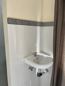 アメッドにあるOle Homestayの白いタイル張りのバスルーム(白いシンク付)