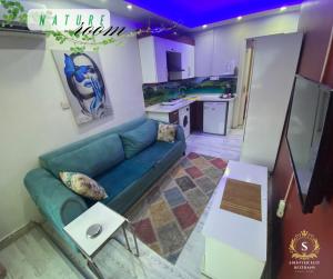 a living room with a blue couch and a kitchen at Şirinyer Elit Residance Apart Hotel in İzmir