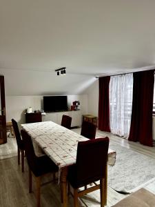 a dining room with a table and chairs and a television at Casa Albă in Vatra Moldoviţei