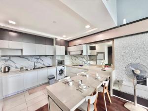 a kitchen with white cabinets and a table and chairs at Riverson Soho Luxury Stay by Finest Homestay in Kota Kinabalu