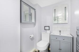 a white bathroom with a toilet and a sink at Reigate - Cosy 1 Bed apartment in Reigate