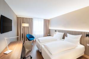 a hotel room with two beds and a tv at NH Hamburg Altona in Hamburg