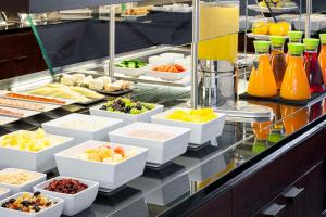 a buffet line with fruits and vegetables in white bowls at NH Hamburg Altona in Hamburg
