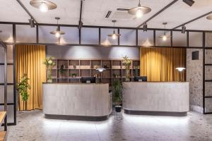a lobby with two reception desks and yellow curtains at NH Hamburg Altona in Hamburg