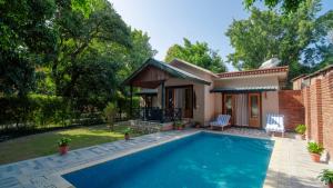 a villa with a swimming pool in front of a house at Tarangi Resort and Spa in Rāmnagar