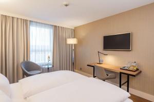 a hotel room with a bed and a desk and a television at NH Hamburg Altona in Hamburg