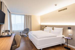 a hotel room with a large white bed and a desk at NH Hamburg Altona in Hamburg