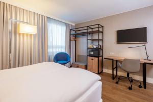 a hotel room with a bed and a desk and a tv at NH Hamburg Altona in Hamburg