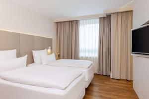 a hotel room with two beds and a flat screen tv at NH Hamburg Altona in Hamburg
