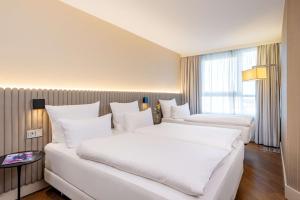 two beds in a hotel room with white pillows at NH Hamburg Altona in Hamburg