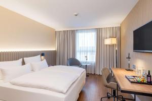 a hotel room with a large white bed and a desk at NH Hamburg Altona in Hamburg