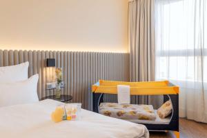 a hotel room with a bed and a baby chair at NH Hamburg Altona in Hamburg