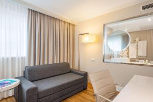 a living room with a couch and a mirror at NH Hamburg Altona in Hamburg