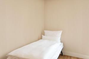 a white bed in a corner of a room at NH Hamburg Altona in Hamburg